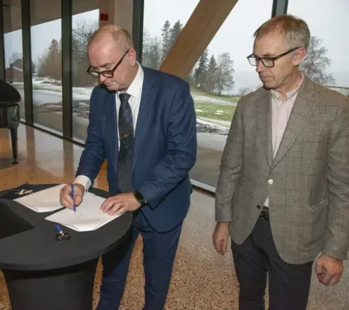 Adm.dir. i Anno, Sven Inge Sunde, signerer overtakelsespapirene for Anno Domkirkeodden historiesenter, mens Øystein Nordal fra hovedentreprenør Martin M. Bakken står ved siden av.