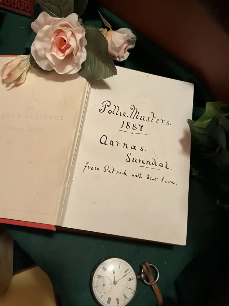 Oppslått bok med blomster og gjenstander rundt.