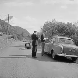 Sivilkledd mann skriver på blokk ved bil under en trafikk te