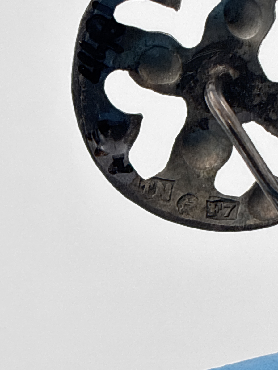 Sjalnål av silver med runt huvud med genombrutet mönster.

Stämpel: 
Årsbokstav: F7 = 1908
Mästarstämpel: okänt
Ortsstämpel: okänt