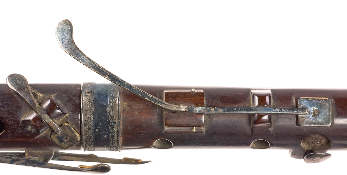 Tvärflöjt i ebenholts med ringar av silver och mörkt horn, med blommönster. 3 delar. C-fot. 8 klaffar med bocklagring och kvadratiska plattor, varav 2 reglerar samma ton: B.