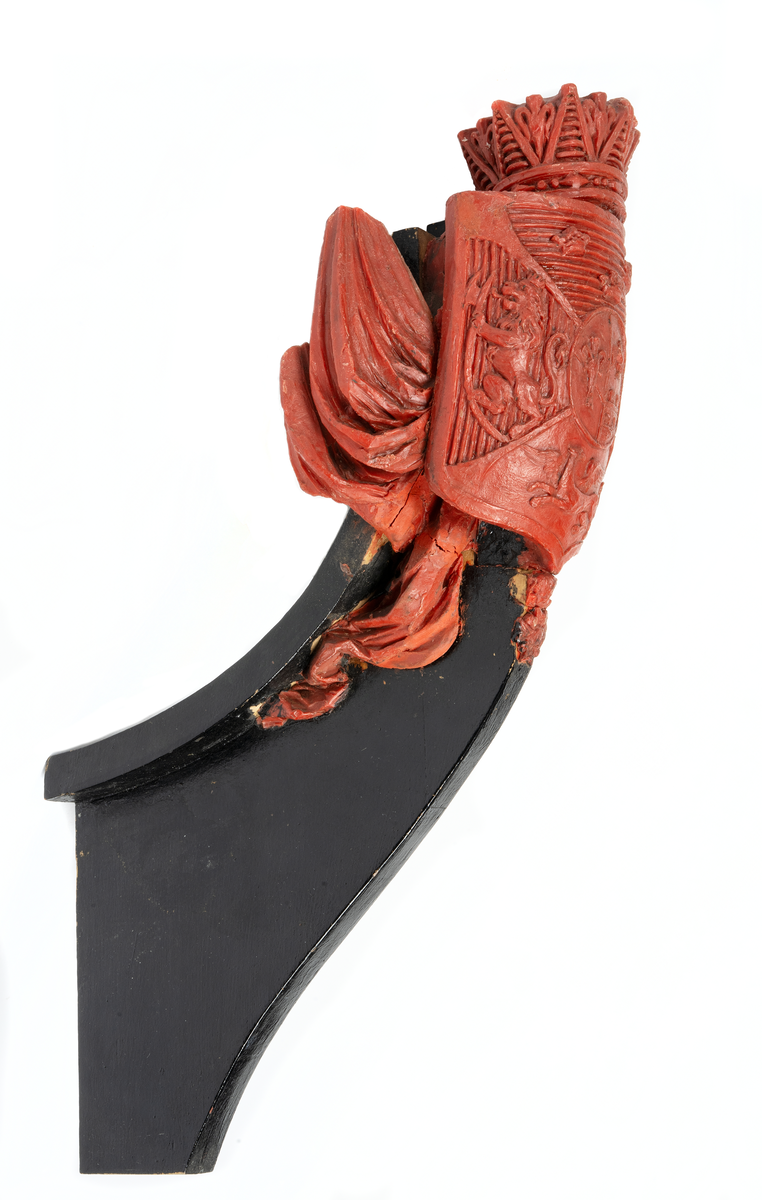 Vapensköld med Bernadottes hjärtvapen samt fyra fält med Sveriges och Norges lejon, en grip samt tre kronor, krönt med hertiglig krona. Hertigen av Södermanland Prins Oscar. Skölden flankeras av två fanor med stänger på var sida. Nedtill serafimerkedja. Monterad till stävkonstruktion av svartmålat trä.