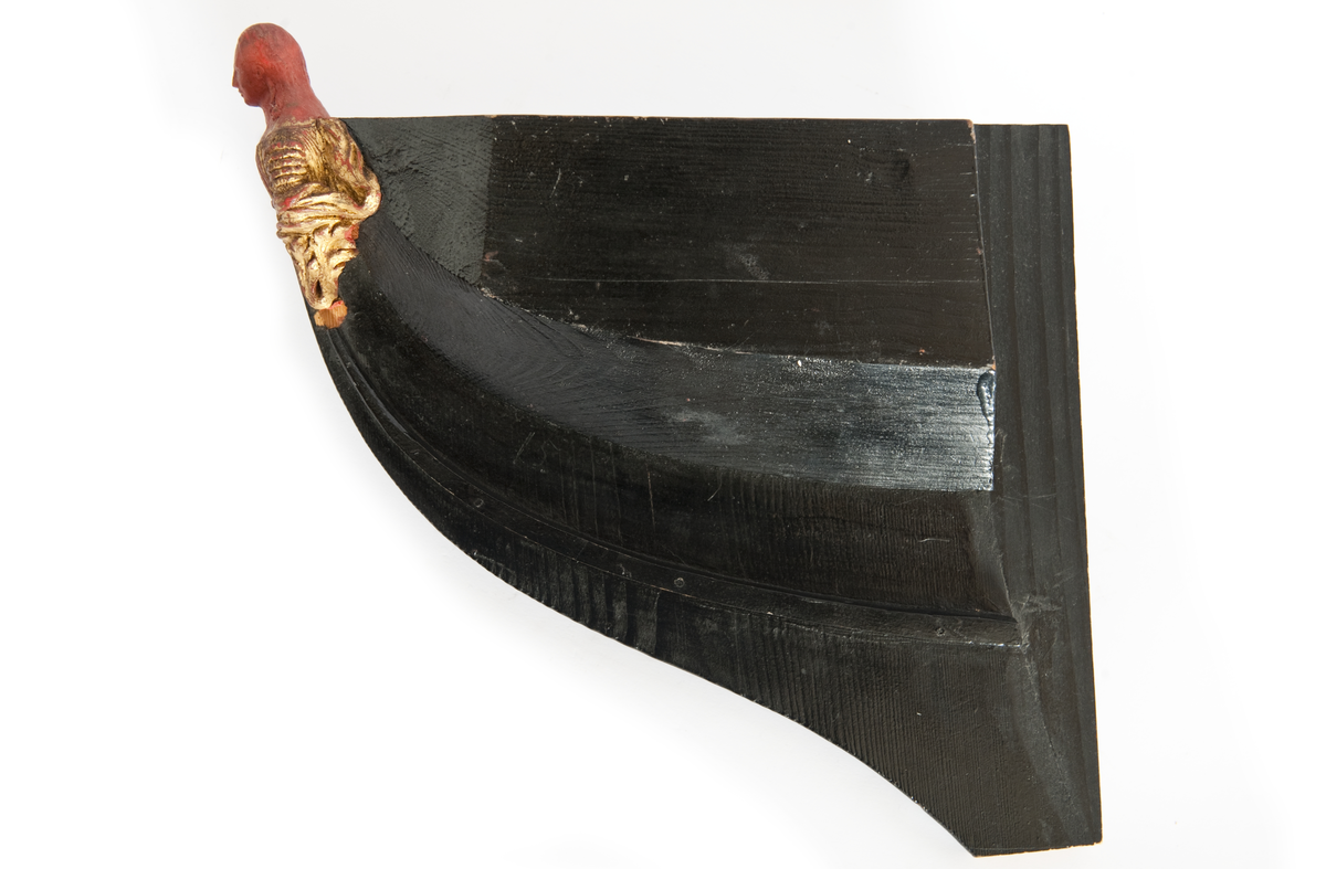 NORRKÖPINGs galjon. Vapensköld krönt av hjälm. På sköldens refflade botten krönt” N” kommandostäv och bila . På sidorna stiliserat bladverk. Monterad på stävkonstruktion av svartmålat trä, bogspröt. Omålat. röd vax