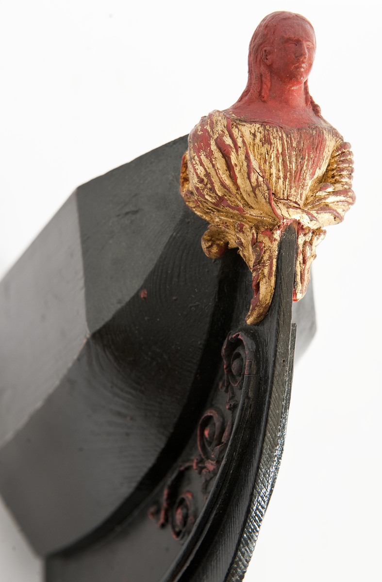 NORRKÖPINGs galjon. Vapensköld krönt av hjälm. På sköldens refflade botten krönt” N” kommandostäv och bila . På sidorna stiliserat bladverk. Monterad på stävkonstruktion av svartmålat trä, bogspröt. Omålat. röd vax