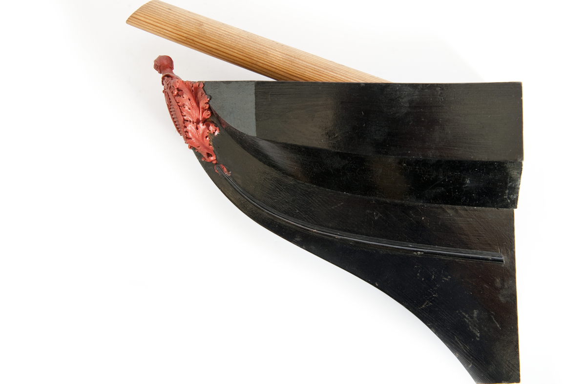 NORRKÖPINGs galjon. Vapensköld krönt av hjälm. På sköldens refflade botten krönt” N” kommandostäv och bila . På sidorna stiliserat bladverk. Monterad på stävkonstruktion av svartmålat trä, bogspröt. Omålat. röd vax