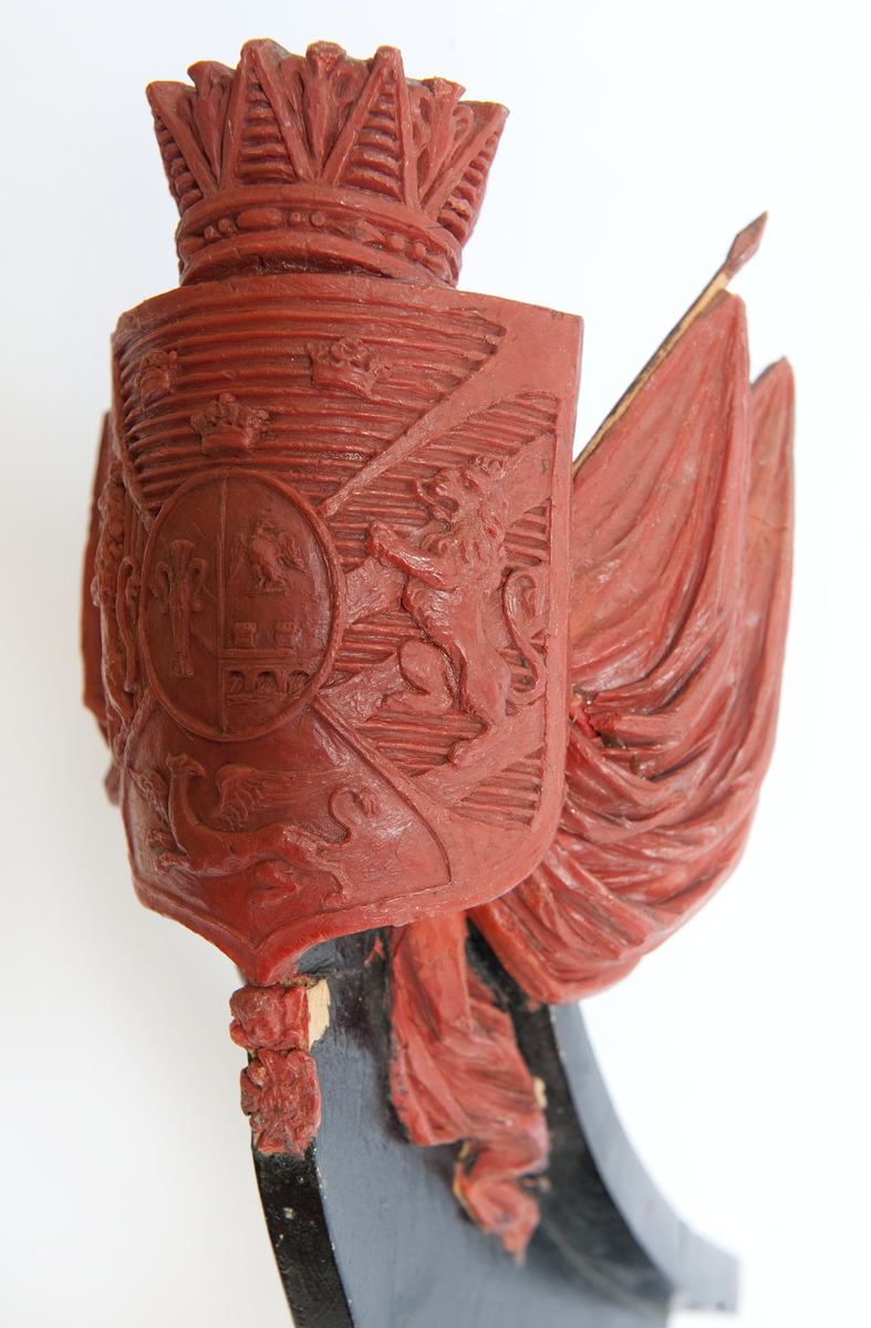 Vapensköld med Bernadottes hjärtvapen samt fyra fält med Sveriges och Norges lejon, en grip samt tre kronor, krönt med hertiglig krona. Hertigen av Södermanland Prins Oscar. Skölden flankeras av två fanor med stänger på var sida. Nedtill serafimerkedja. Monterad till stävkonstruktion av svartmålat trä.