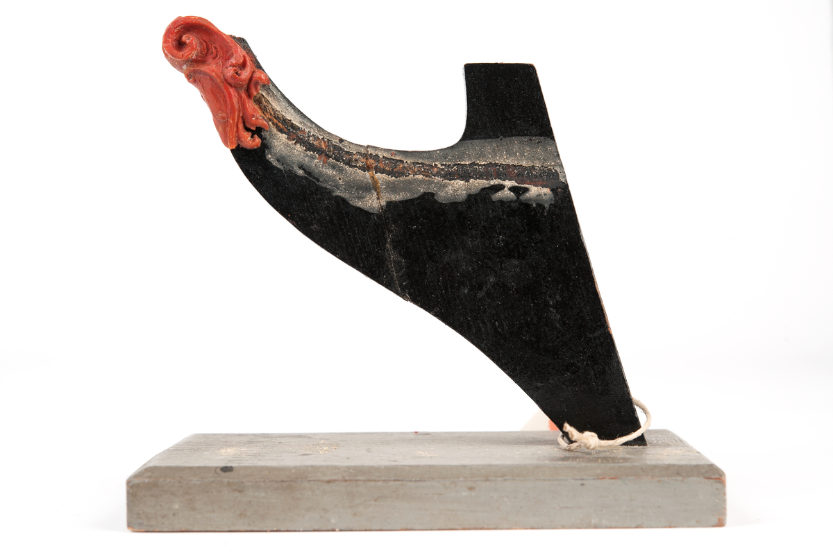 Fregatten JOSEPHINEs galjon. Bilden helt bortfallen men har varit monterad till stävkonstruktion av svartmålat trä, fästad till gråmålad träplatta. Plattan: 150x90 mm. Röd vax, bilden bortfallen.