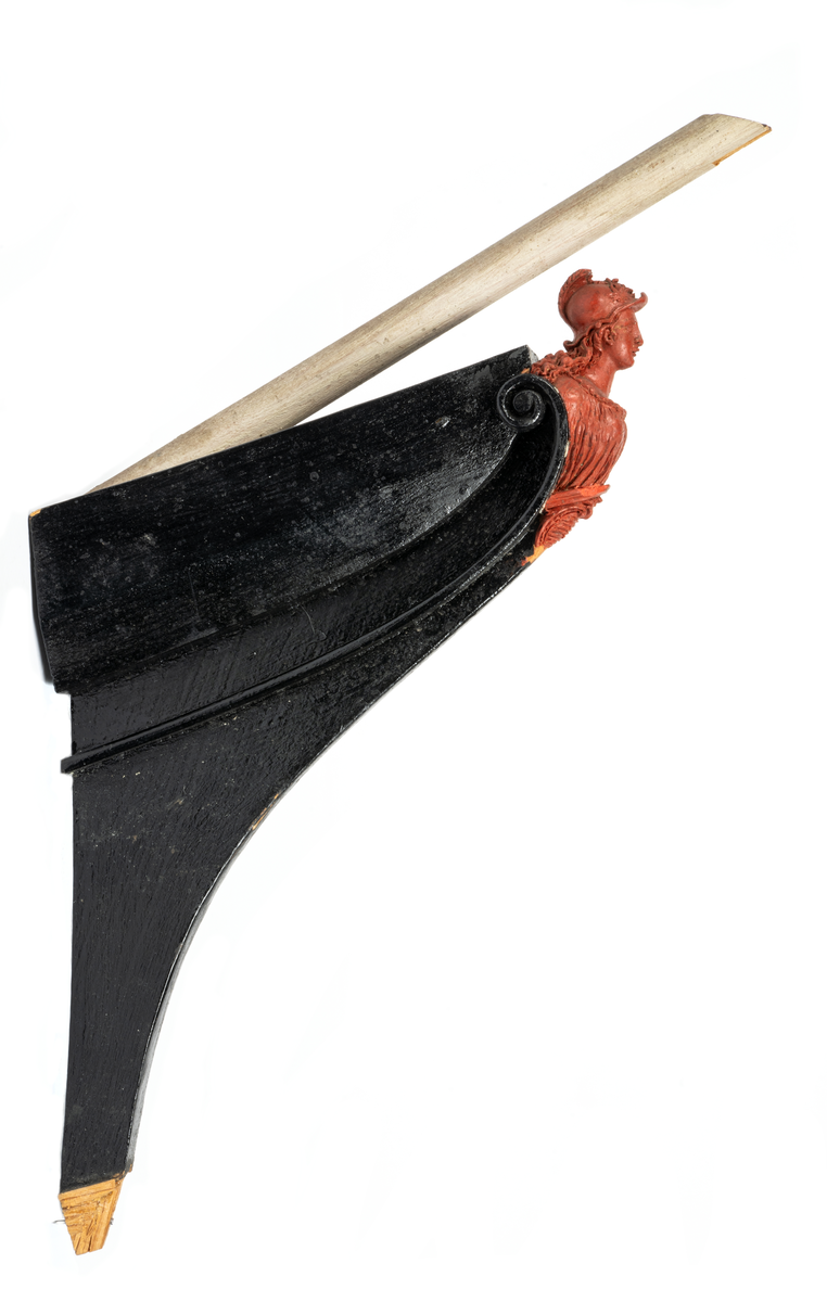 Chefsfartyget VALKYRIANs galjon. Kvinnobyst i grekisk  dräkt med hjälm, sockel med vapenplåt. Monterad  på stävkonstruktion av svartmålat trä, med del av gråvitmålat bogspröt. Allt på mörkgråmålad platta. 160X85 mm. Röd vax.