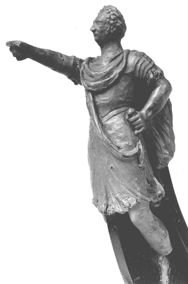 Förestäler Linjeskeppet Carl XIV Johans galjon. Mansfigur, Carl XIV Johan i  romersk dräkt. Höger arm avslagen. Monterad till
stävkonstruktion av svartmålat trä. Röd vax.