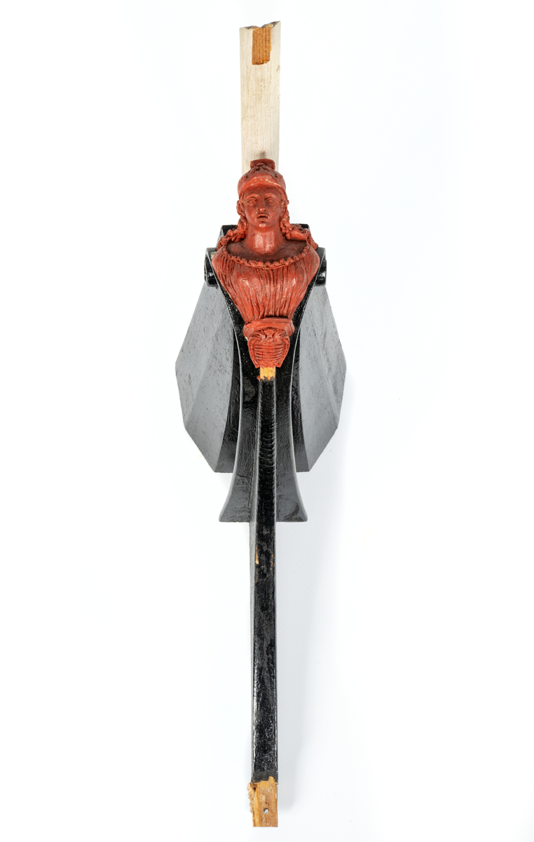 Chefsfartyget VALKYRIANs galjon. Kvinnobyst i grekisk  dräkt med hjälm, sockel med vapenplåt. Monterad  på stävkonstruktion av svartmålat trä, med del av gråvitmålat bogspröt. Allt på mörkgråmålad platta. 160X85 mm. Röd vax.