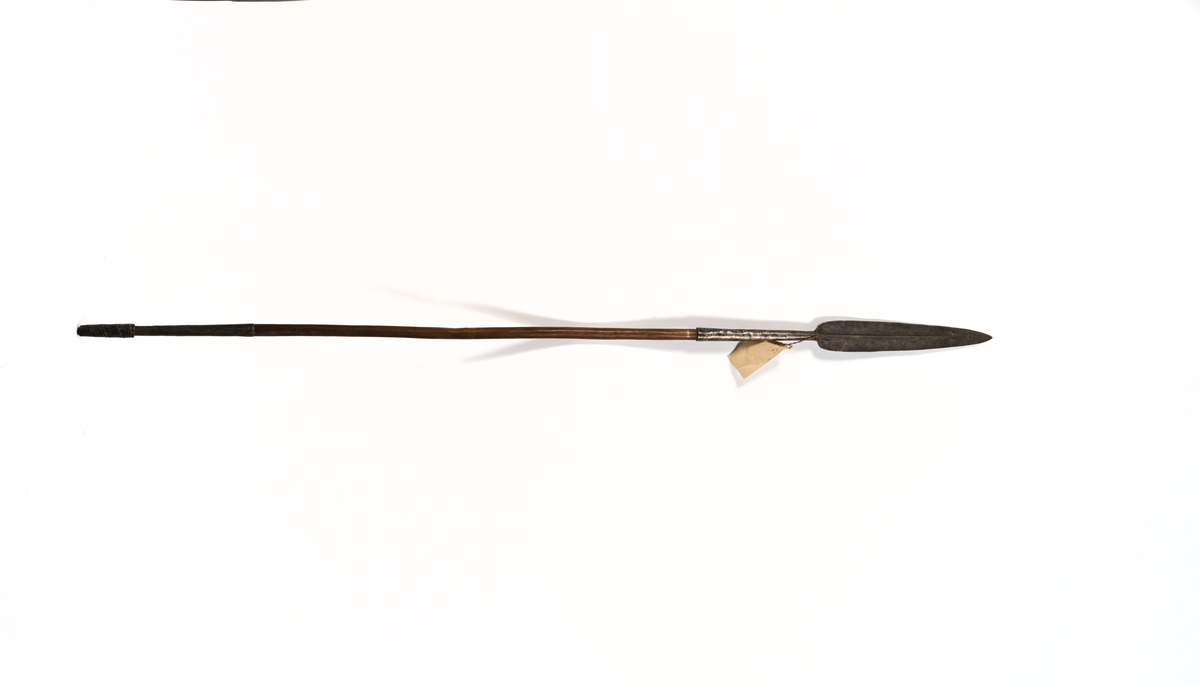 Hordapik, Afrika. Spets av smitt järn, bredbladig, tvåeggad med långt hylsfäste skaft av hårt träslag med lång doppsko av järnplåt nedtill virad till en klump.
Från fregatten VANADIS världsomsegling 1883-1885.
Gåva: Amiral Lindmans sterbhus 1937.