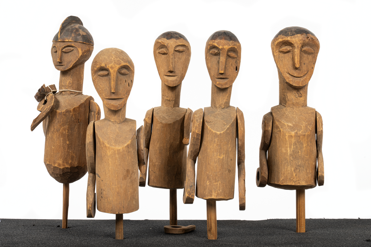 Modell av kanot från Samoa, skuren ur en stam av balsaliknande trä med relingen urhakad för tio tvärsgående balkar. Till modellen hör 5 snidade mansfigurer, fem paddlar, en fågel och fyra olika snidade tofter eller dylikt. Flera smärre skador. Större skada i aktern.