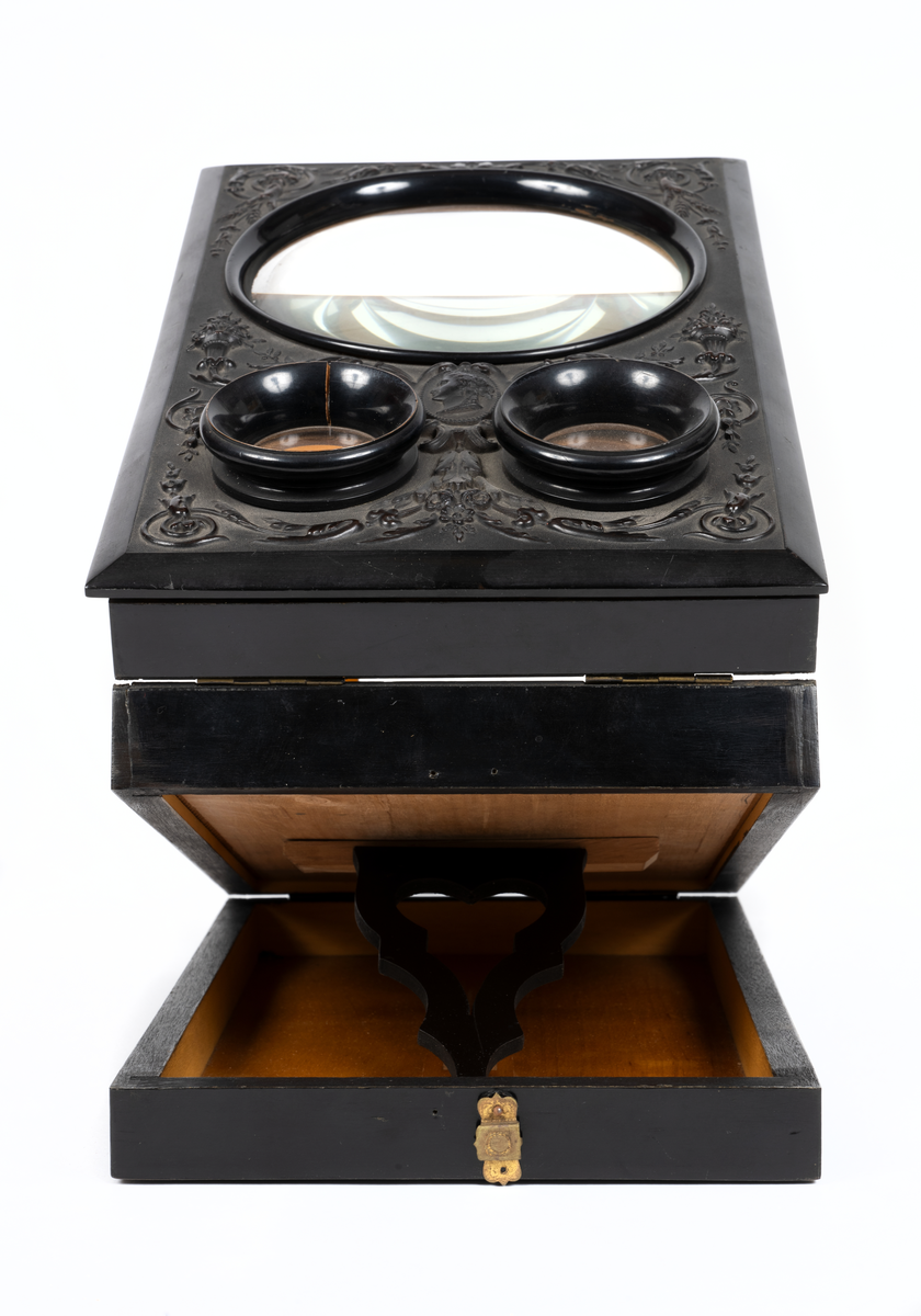 Svarlackad stereoskop med dekorerad ovansida och tre linser. Tillbehör finns.