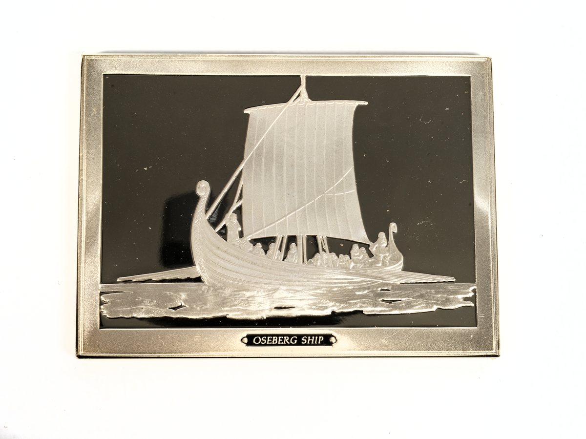 Rektangulär silverplakett föreställande Osebergsskeppet från 800-talet.