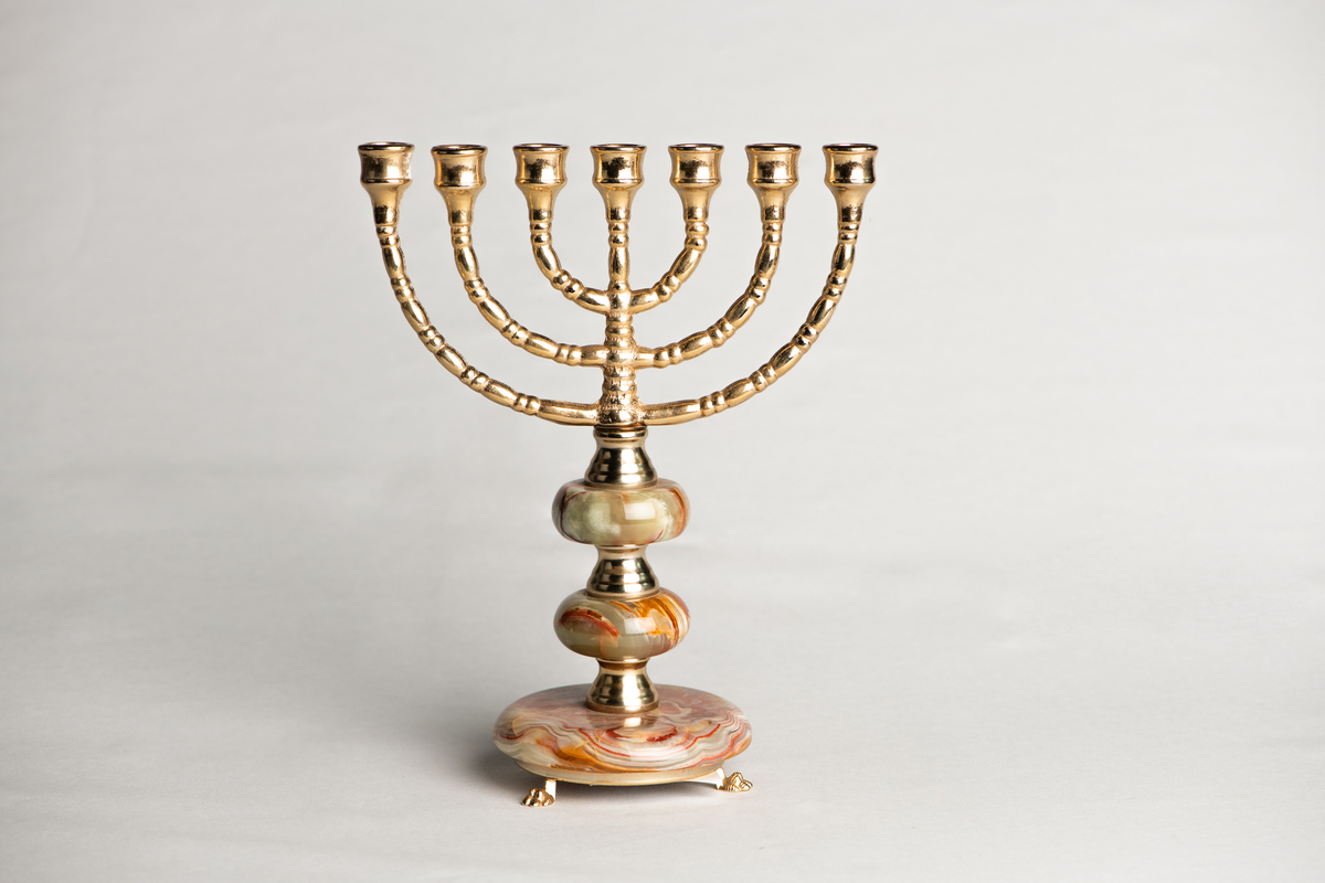 Liten lysestake i metall og stein. Metallet er gullfarget, mens steinen er hvit og rosa. Lysestaken har plass til 7 små lys. Foten er hovedsakelig av stein, i 3 stk. sirkulære deler som blir større nedover. Helt nederst har lysestaken 3 stk. små dyreføtter i gullfarget metall.