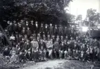 Företrädelsevis den yngre arbetsstyrkan vid Reijmyre glasbruk samlade för fotografering runt hyttmästaren. Foto 1902 möjligen 1903.