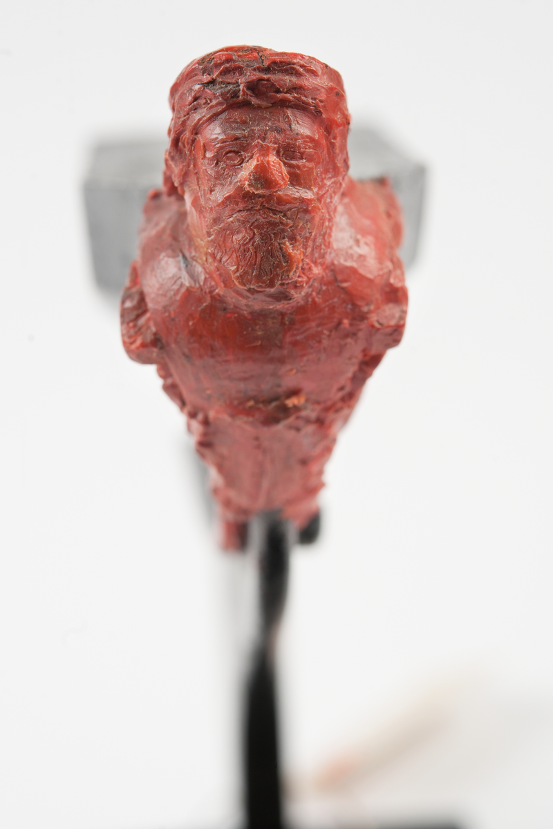 Ångkorvetten THORs galjon. Bröstbild av guden Thor  med hammare och brandfackla, samt akantusblad. Modelleringen skisserad. Monterad på stävkonstruktion av svartmålat trä, fästad till platta. Platta: 175x100 mm. Röd vax.