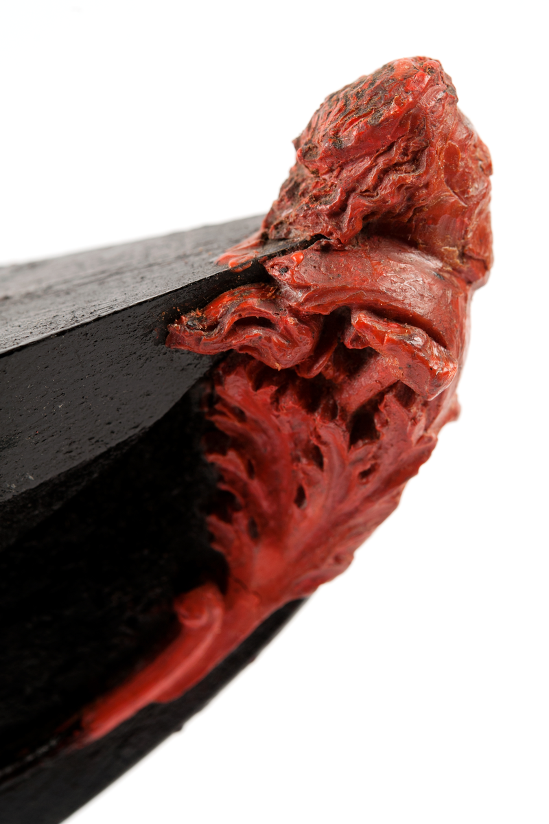 Ångkorvetten THORs galjon. Bröstbild av guden Thor  med hammare och brandfackla, samt akantusblad. Modelleringen skisserad. Monterad på stävkonstruktion av svartmålat trä, fästad till platta. Platta: 175x100 mm. Röd vax.