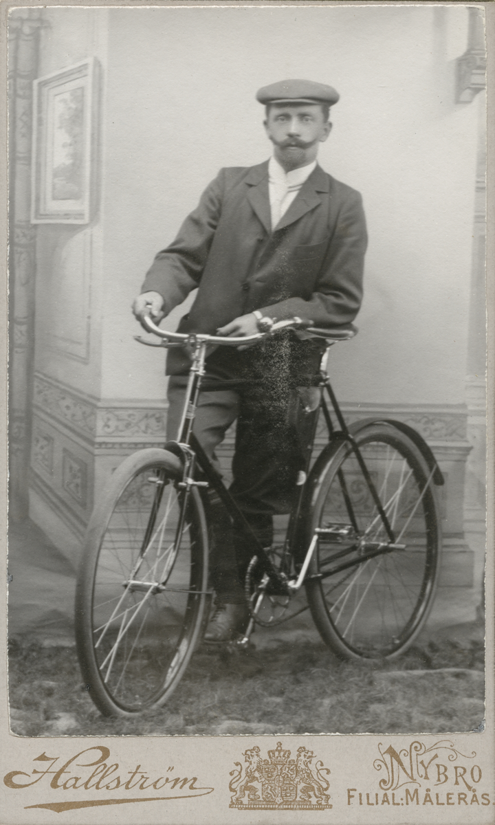 Porträtt av en man som står lutad mot en cykel.