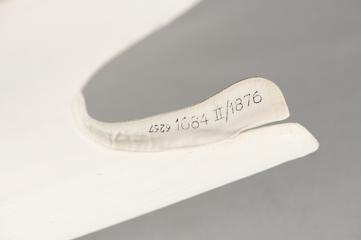 Løst skjortebryst i  barnestørrelse. Hvit, med 3 motfolder, 1 perlemorsknapp. 