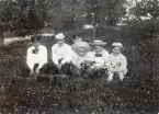 Margaretha Bergstedt (5:a fr. v.) tillsammans med några pojkar (kusiner?) på en gräsmatta i en park.