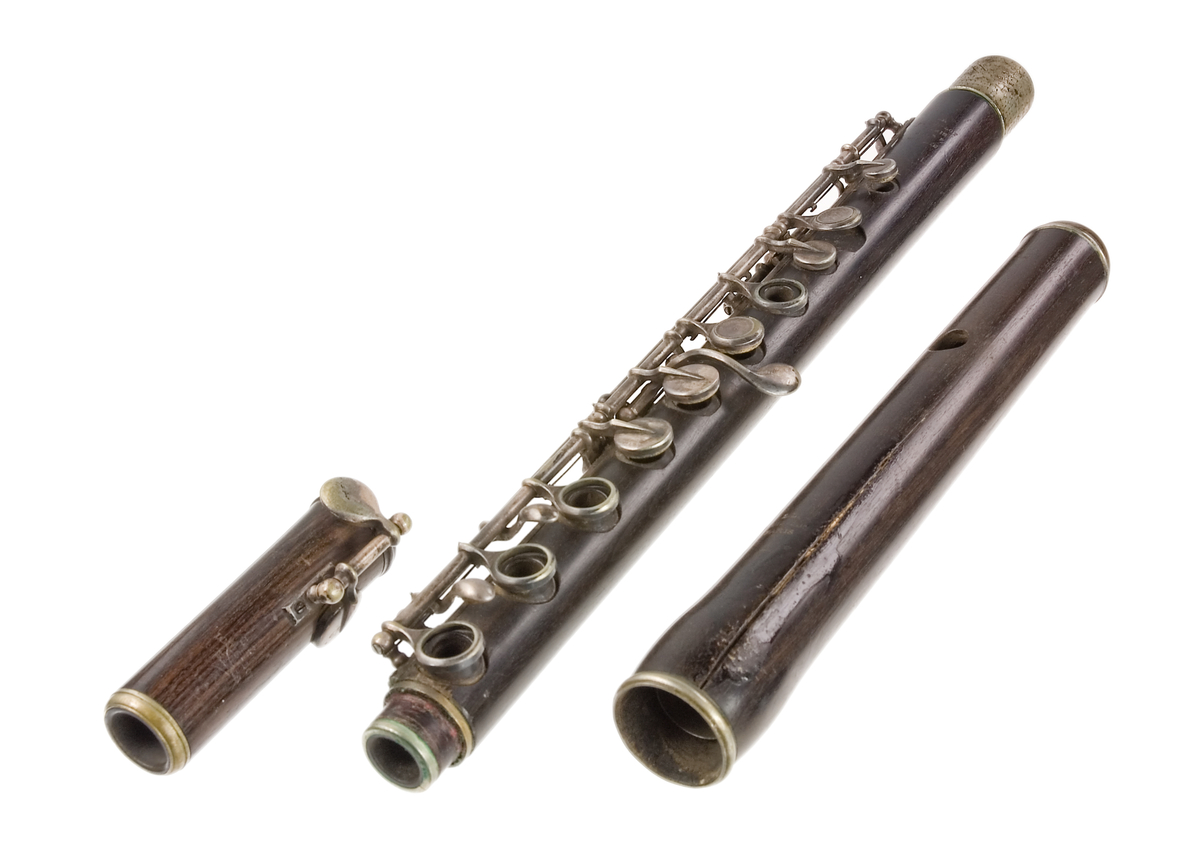 Tvärflöjt i mörkt trä med metallringar. Böhmsystem, delvis med öppna klaffar. 3 delar. Sprickor i munstycke. Fot ej original. Dålig kondition. A=459.