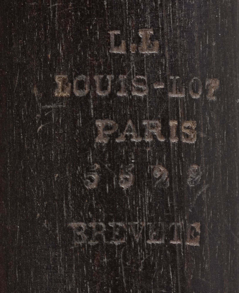 Tvärflöjt i mörkt trä med metallringar. Böhmsystem, delvis med öppna klaffar. 3 delar. Sprickor i munstycke. Fot ej original. Dålig kondition. A=459.