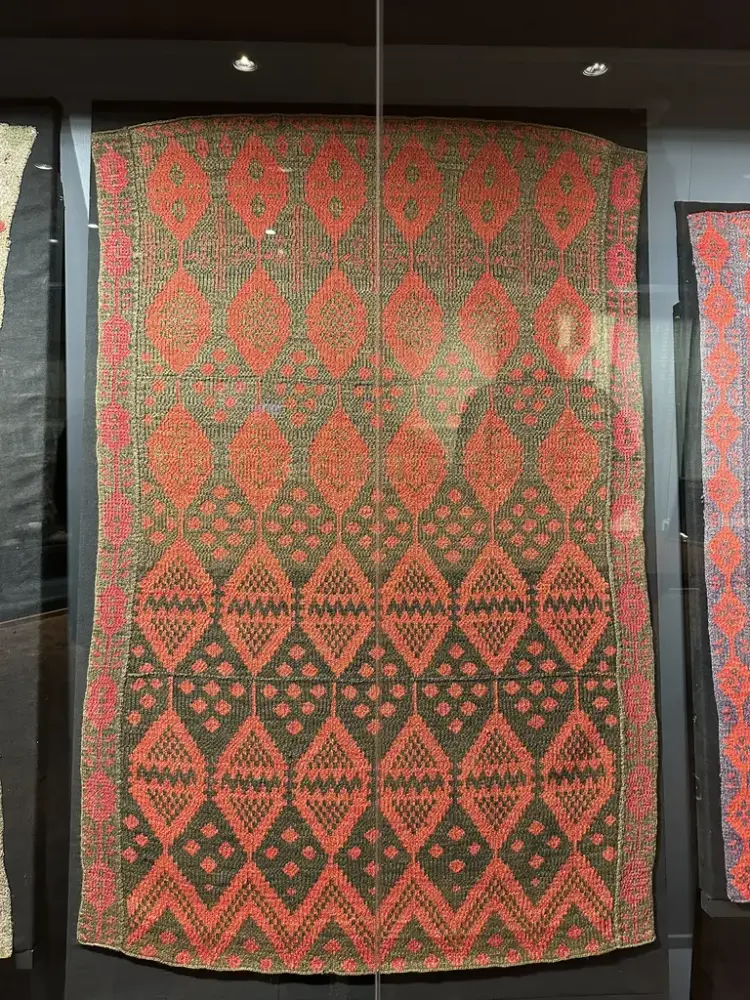 Stickat täcke i röd och brun tråd