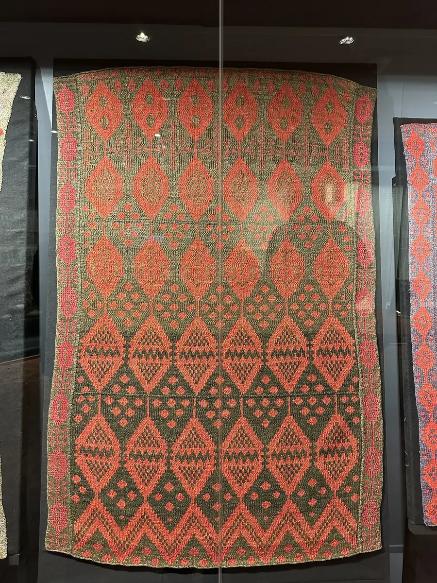 Stickat täcke i röd och brun tråd