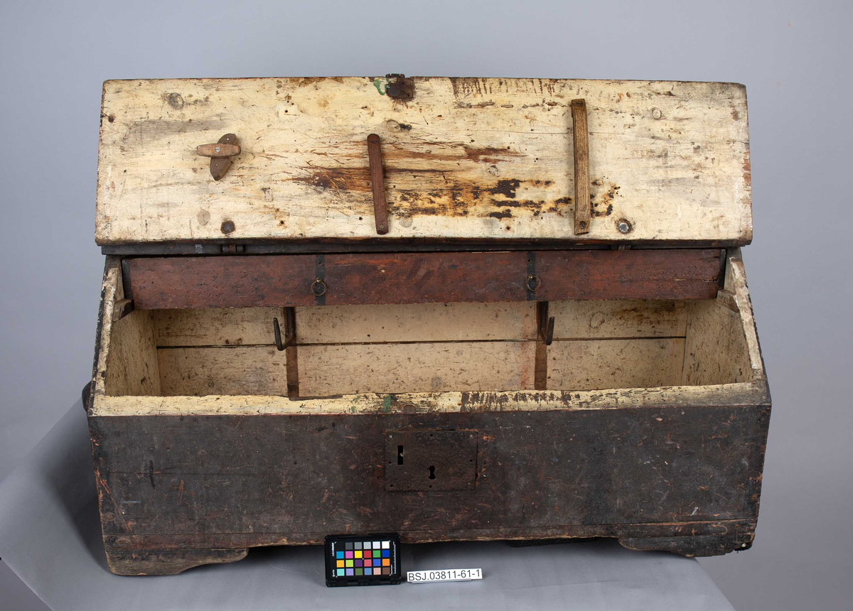 Tømmermannskiste. Kiste med åpning i front med beslag av jern for feste av lokk samt låskasse. Trehåndtak på hver kortside. Innvendig løs skuff og opphengsbeslag for bor og navar ol.