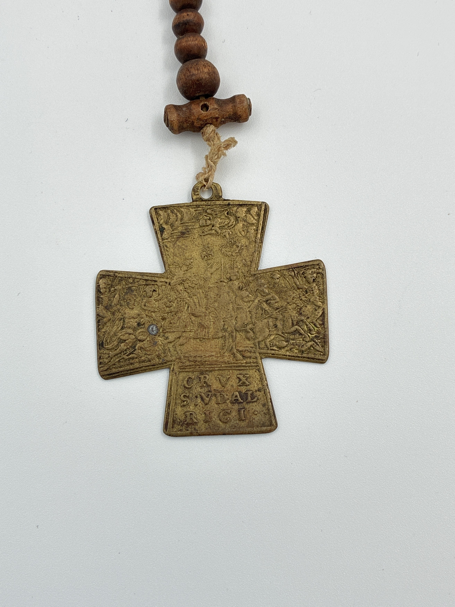 Radband med träkulor och mässingskors i form av ett Sankt Georgskors. På ena sidan av korset en scen kopplad till Lechfeldslaget 955 e.Kr samt texten "CRVX S:VDAL RICI" vilket syftar på att korset är tillägnat Sankt Ulrik. 

På korsets andra sida syns Sankt Ulrik, Sankt Benedikt och Sankt Afra. 

En gåva till givaren av rådman Siljeström.