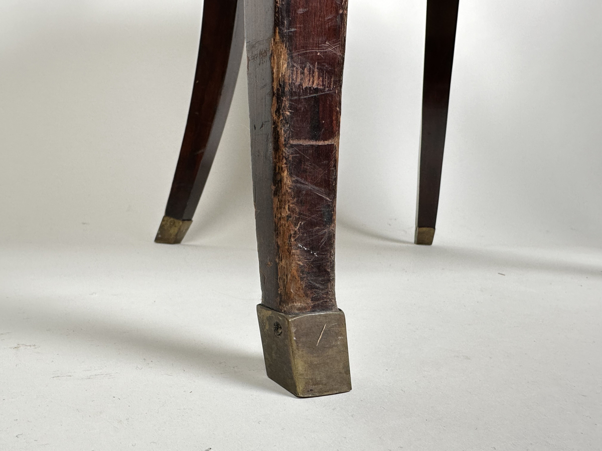 Stol, karmstol. Av polerad, mörkt betsad björk. Mjuk, rundad form med slät ryggbricka, så när som på små skurna volut i dess övre hörn. Ryggståndarna dekorerade med kapitäl i mötet med ryggbrickan. Främre stolsbenen med kulavslut upptill. Samtliga stolsben aningen svängda samt skodda med mässingskor. Sits stoppad och klädd med mörkt grå (troligtvis) pergamoid, fäst med runda, släta nitar. Sekundär sadelgjord undertill av fastnålade tygstycken.