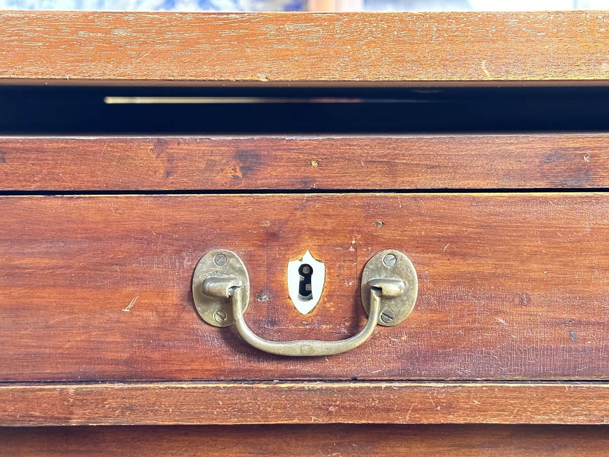 Bordsskiva med sarg till skrivbord, av fernissat och polerat lövträ samt blindträ av furu. Rektangulärt blad klätt med grön filt. Underliggande sarg med plats för extraskiva, samt fem utdragbara lådor - tre på skrivarsidan och två på andra. Samtliga lådor med handtag i mässing samt nyckelskylt formad som en sköld, av vitt material - möjligtvis elfenben.