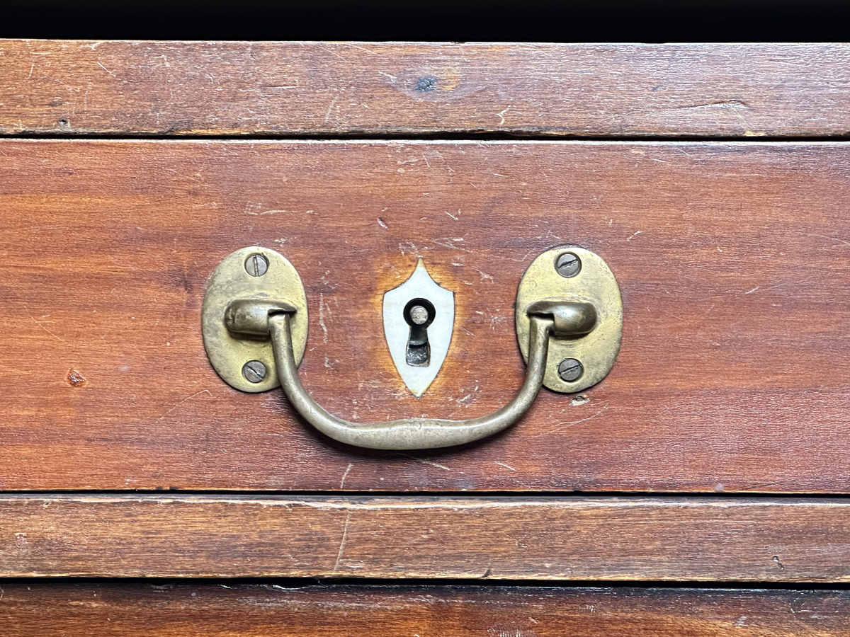 Bordsskiva med sarg till skrivbord, av fernissat och polerat lövträ samt blindträ av furu. Rektangulärt blad klätt med grön filt. Underliggande sarg med plats för extraskiva, samt fem utdragbara lådor - tre på skrivarsidan och två på andra. Samtliga lådor med handtag i mässing samt nyckelskylt formad som en sköld, av vitt material - möjligtvis elfenben.