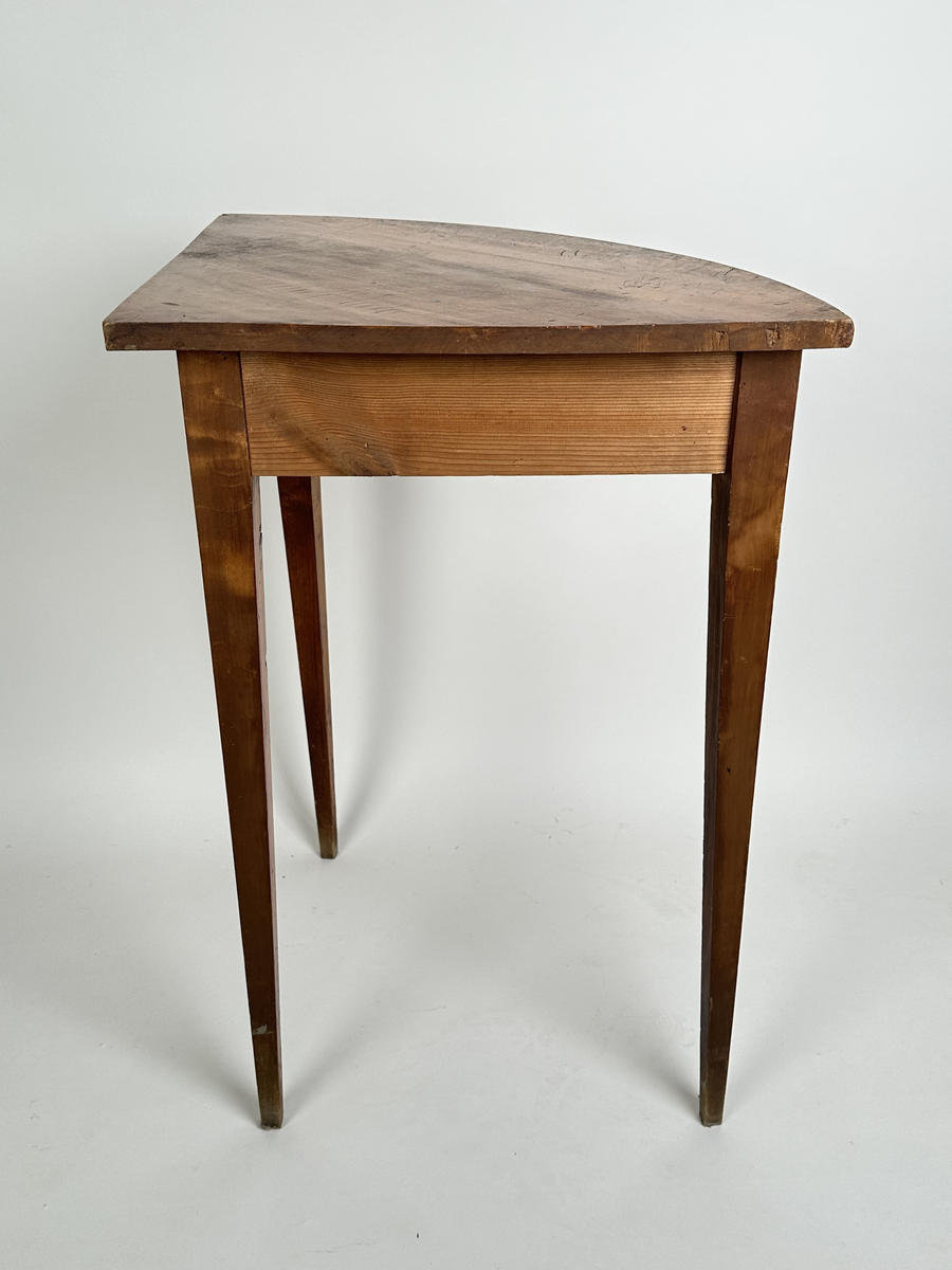 Bord, hörnbord av polerad och fernissad björk samt furu. Kvartscirkelformat blad med välvd sarg. Tre stycken raka, fyrkantiga ben som avsmalnar något nedåt. Flammigt med brukspatina.