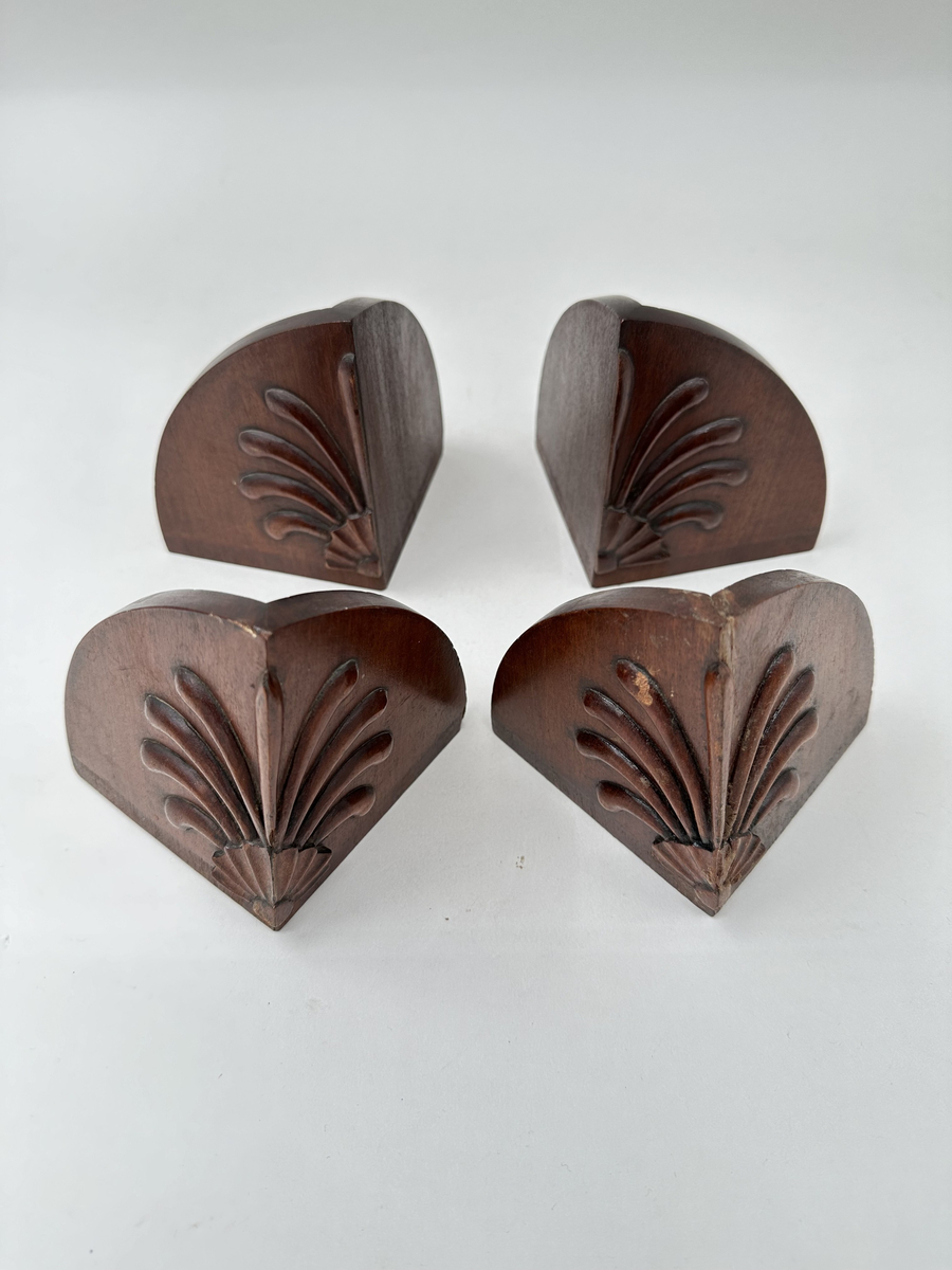 Bokskåp i mahogny med glasdörrar och låda nederst. Gavelformat överstycke med plats för fyra hörnkrön. Två krön har blomornament på två sidor, de andra två krönen har endast ornament på den ena sidan. Fem hyllplan, 20 platta hyllbärare i metall. Hålen för hyllbärarna klädda i mässing. Glasdörrarna med snidade dekorationer i form av bland annat cirklar och pilar. Dekorativa konsoler på bägge sidor dörrarna. Nyckelbrickor till dörrar och låda i ben.