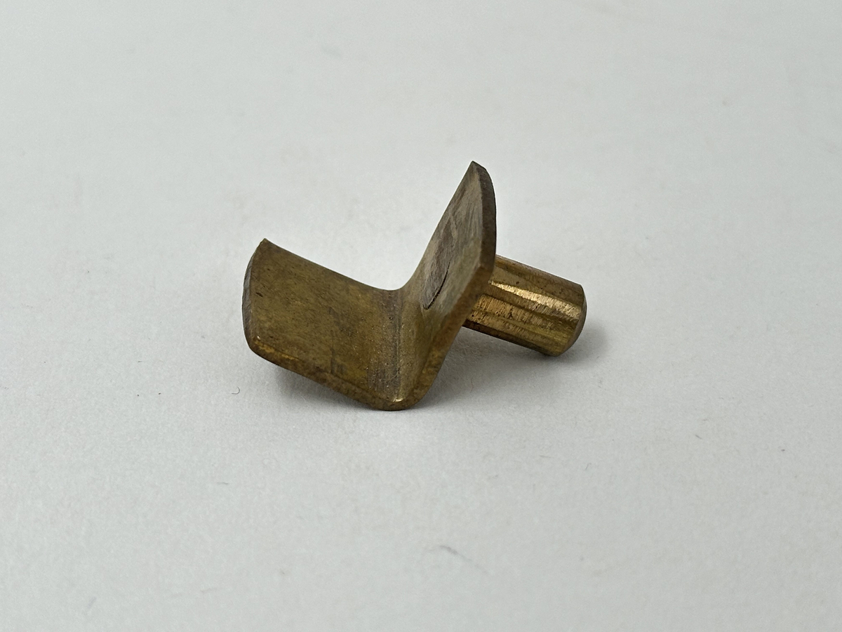 Bokskåp i mahogny med glasdörrar och låda nederst. Gavelformat överstycke med plats för fyra hörnkrön. Två krön har blomornament på två sidor, de andra två krönen har endast ornament på den ena sidan. Fem hyllplan, 20 platta hyllbärare i metall. Hålen för hyllbärarna klädda i mässing. Glasdörrarna med snidade dekorationer i form av bland annat cirklar och pilar. Dekorativa konsoler på bägge sidor dörrarna. Nyckelbrickor till dörrar och låda i ben.