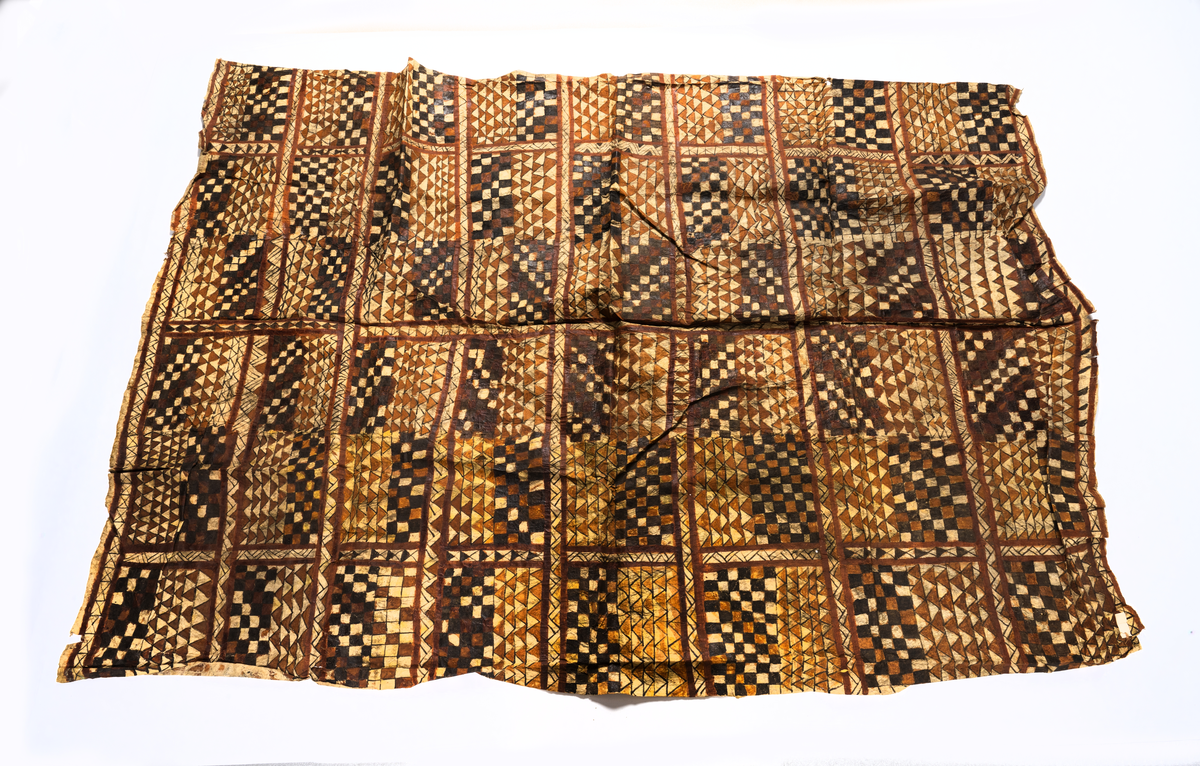 Tapa från Samoa.
Mönster i svartbrun färg indelad på längden i åtta fält med rutor och trianglar.