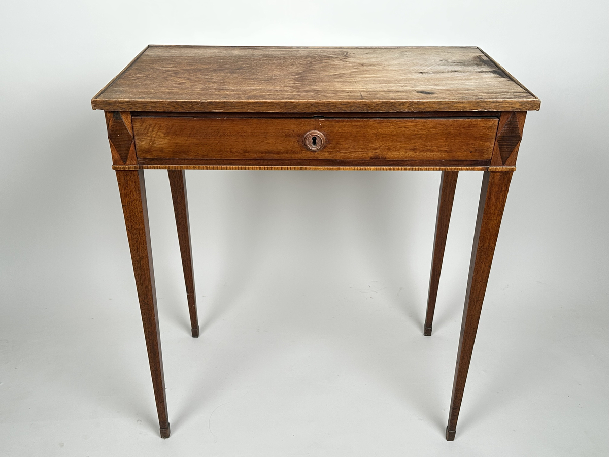 Bord, sengustavianskt. Furu med mahoganyfanér. Fyrkantiga, raka ben med avsmalning neråt och definierade avslut. Sarg med rombformad dekor i relief i samtliga hörn. I sargen låda med fackinredning. På lådans front infälld låskista med rund, dekorativ nyckelskylt i trä. Blad i slitet och fuktskadat skick.