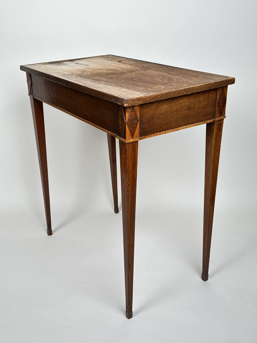 Bord, sengustavianskt. Furu med mahoganyfanér. Fyrkantiga, raka ben med avsmalning neråt och definierade avslut. Sarg med rombformad dekor i relief i samtliga hörn. I sargen låda med fackinredning. På lådans front infälld låskista med rund, dekorativ nyckelskylt i trä. Blad i slitet och fuktskadat skick.