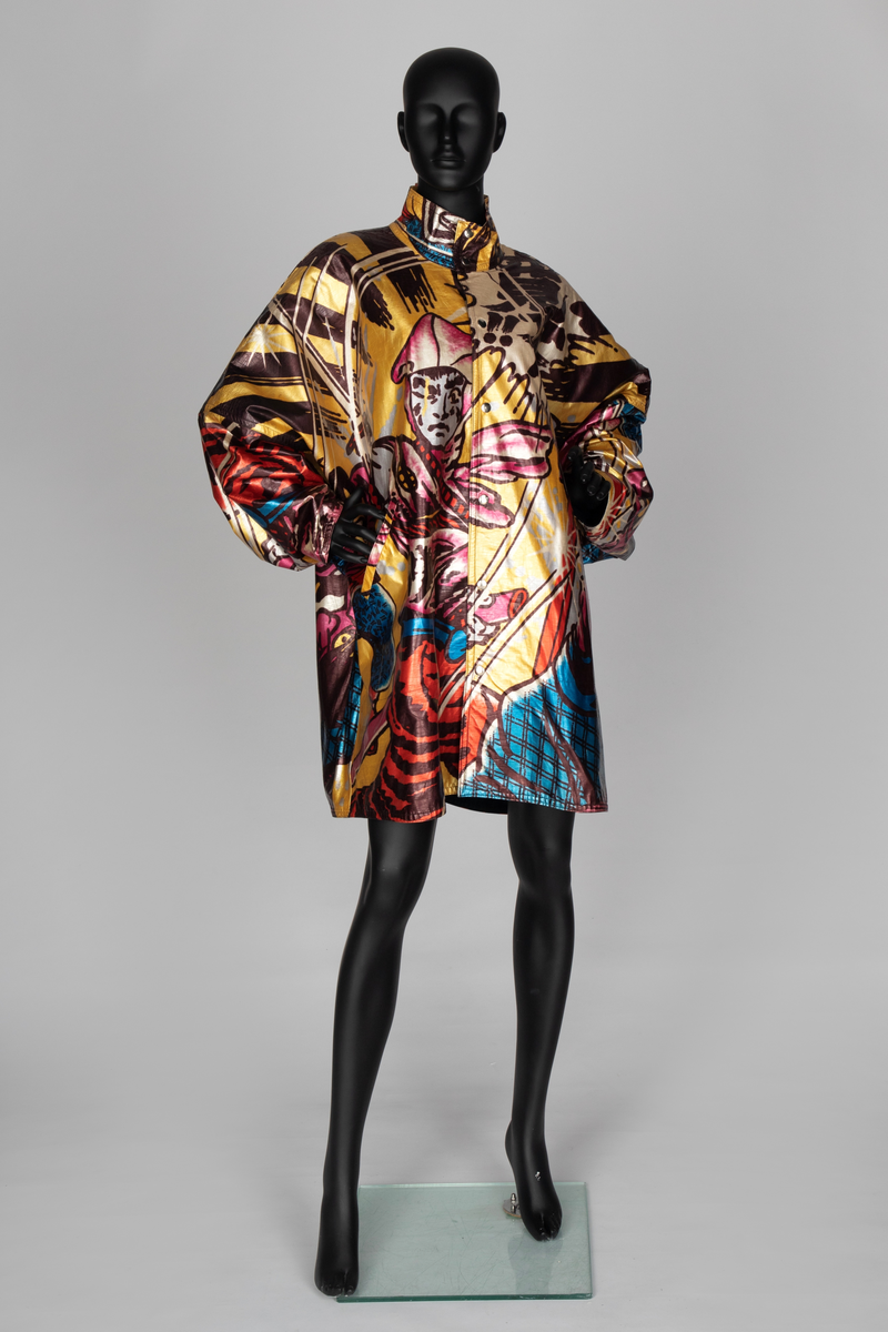 Jakke av vinyl i fargene rosa, blå, brun, rød og gul med motiv av samurai i tegneseriestil. Jakken er romslig, har rette linjer, nedsenket skulder, dypt ermhull og høy halslinning. Lukkes med trykknapper. Fôret med svart stoff.