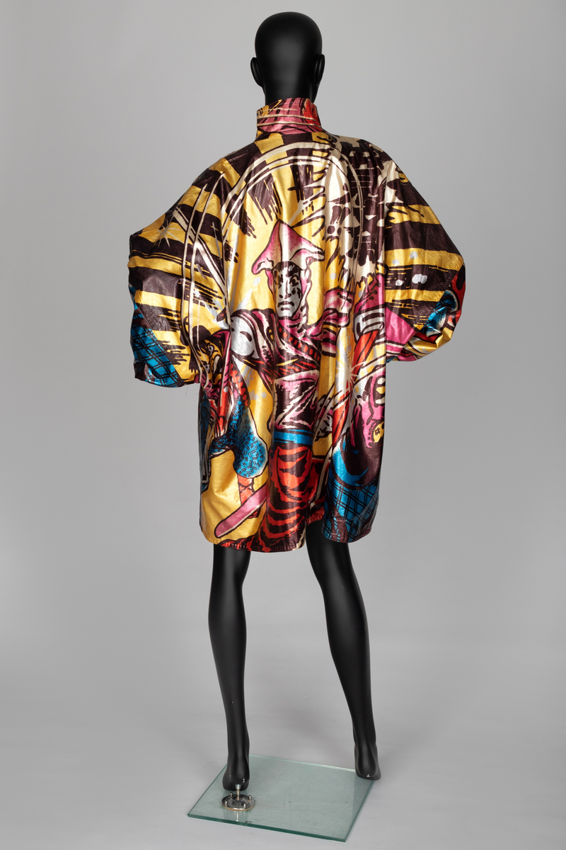 Jakke av vinyl i fargene rosa, blå, brun, rød og gul med motiv av samurai i tegneseriestil. Jakken er romslig, har rette linjer, nedsenket skulder, dypt ermhull og høy halslinning. Lukkes med trykknapper. Fôret med svart stoff.