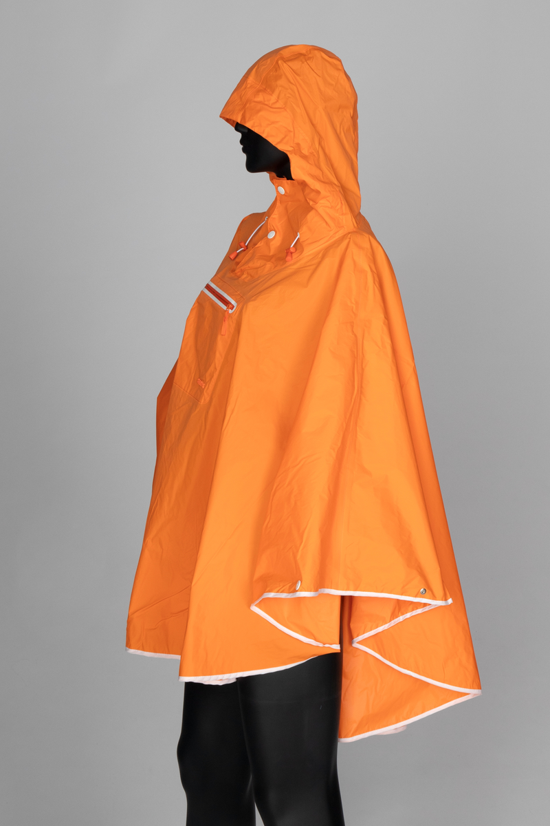 Oransje regnponcho med hette. Ponchoen har en løsthengende sirkelform. Trykknapper nederst til ermene og hvit skråkant på nederkanten. Hette med åpning og to hvite trykknapper. Snor og maljer med snorstopper og snorregulerer. Midt foran på brystet sveiset glidelås, markert med hvit kant.