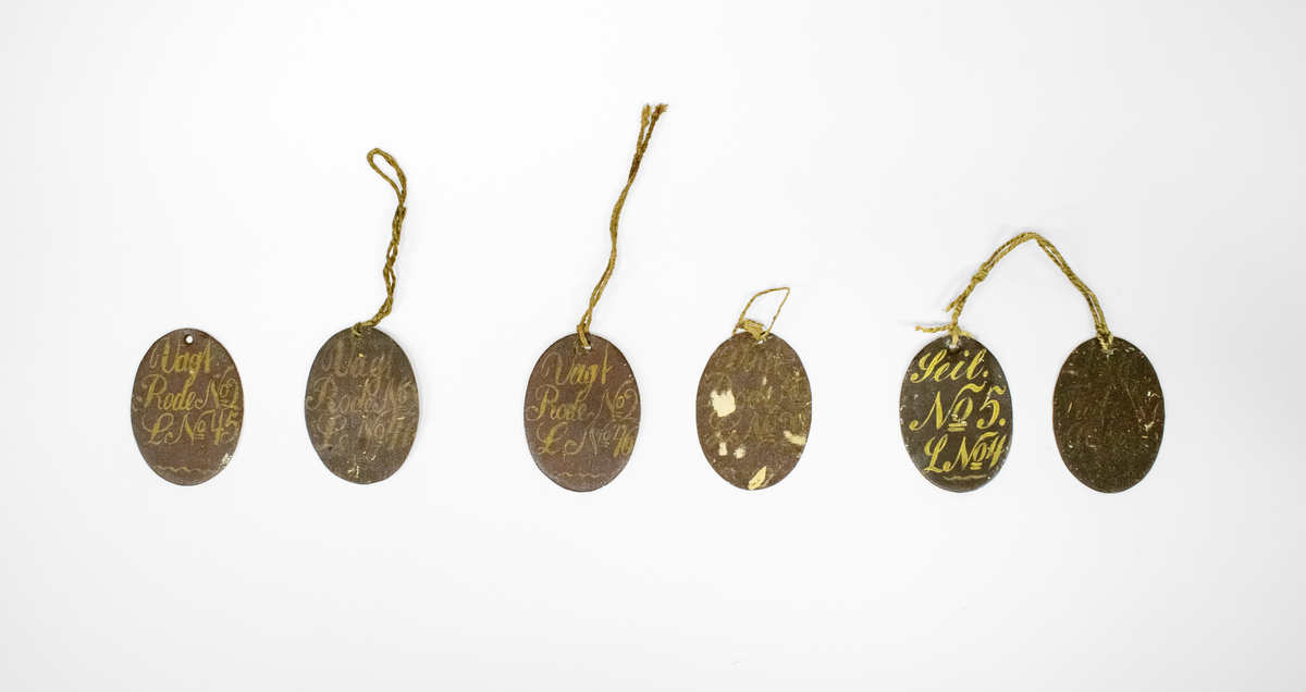 Ulike skilt av metall, antagelig for Brannmannskap. Alle skiltene har håndmalt skrift og dekor.

Består av 6 små ovale skilter:
1. Vagt, Rode No2, L No45
2. Vagt, Rode No2, L No46
3. Vagt, Rode No2, L No46
4. Vagt, Rode No?, L No?
5. Seil No5., L nO4
6. ?

Og to litt større ovale skilter:
7. Adjutant
8. Rodemester

Og to halvmåneformede skilter:
9. Leutnant No2
10. Leutnant No2
