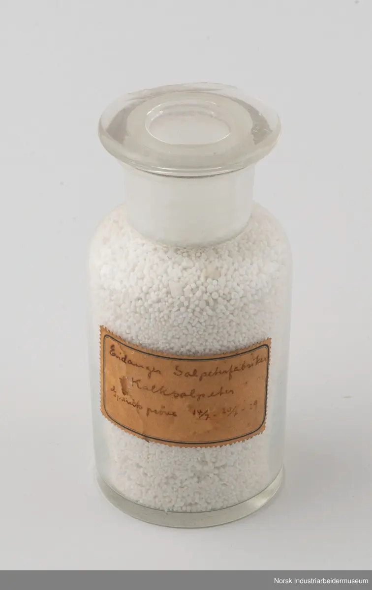Åtte sylindriske laboratorieflasker i glass som inneholder kalksalpeter-prøver fra 1929, 1931 og 1932.
1. Gjennomsnittsprøve ferdigvare 23/6 - 29/6 . 1929
2. Gjennomsnittsprøve ferdigvare 14/7 - 20/7 . 1929
3. Gjennomsnittsprøve ferdigvare 21/7 - 27/7 . 1929
4. Salpeterprøve sendt til Tyskland 27/7. 1929
5. Gjennomsnittsprøve ferdigvare 26/7 - 2/8 . 1929
6. Gjennomsnittsprøve ferdigvare 18/8 - 24/8 . 1929
7. Gjennomsnittsprøve ferdigvare 20/3 - 31/3 . 1931
8. Gjennomsnittsprøve ferdigvare 18/1 - 25/1 . 1932