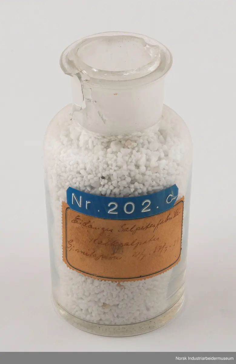 Åtte sylindriske laboratorieflasker i glass som inneholder kalksalpeter-prøver fra 1929, 1931 og 1932.
1. Gjennomsnittsprøve ferdigvare 23/6 - 29/6 . 1929
2. Gjennomsnittsprøve ferdigvare 14/7 - 20/7 . 1929
3. Gjennomsnittsprøve ferdigvare 21/7 - 27/7 . 1929
4. Salpeterprøve sendt til Tyskland 27/7. 1929
5. Gjennomsnittsprøve ferdigvare 26/7 - 2/8 . 1929
6. Gjennomsnittsprøve ferdigvare 18/8 - 24/8 . 1929
7. Gjennomsnittsprøve ferdigvare 20/3 - 31/3 . 1931
8. Gjennomsnittsprøve ferdigvare 18/1 - 25/1 . 1932