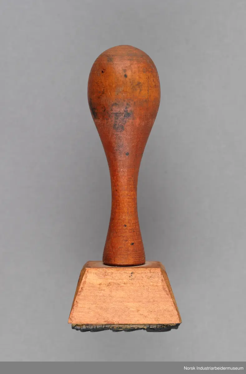 Stempelet har håndtak i lakkert tre.