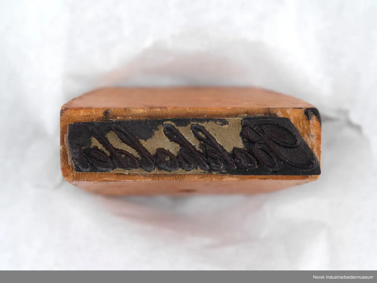 Stempelet har håndtak i lakkert tre.