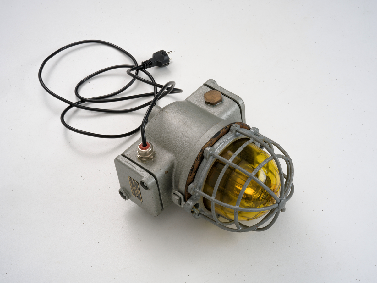 Signallampe med kuppel av glass og to avtagbare deksler som er festet med skruer.