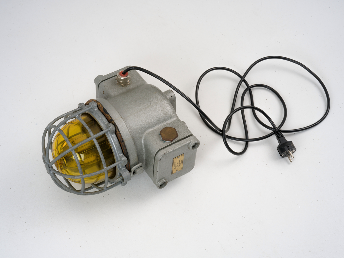 Signallampe med kuppel av glass og to avtagbare deksler som er festet med skruer.